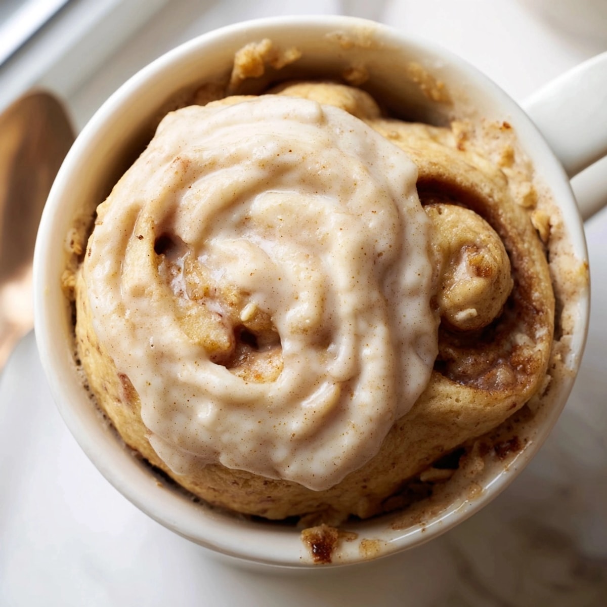 Warm, gooey Protein Cinnamon Roll Mug Cake, topped with creamy yogurt frosting, ready to eat!