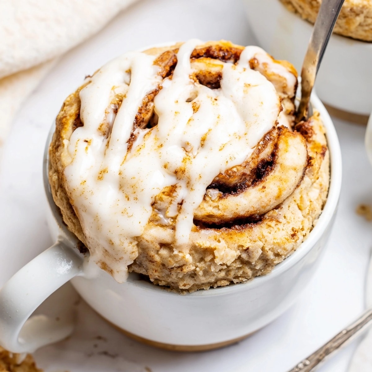 Easy single-serving Protein Cinnamon Roll Mug Cake, great for breakfast, still steaming in its mug.