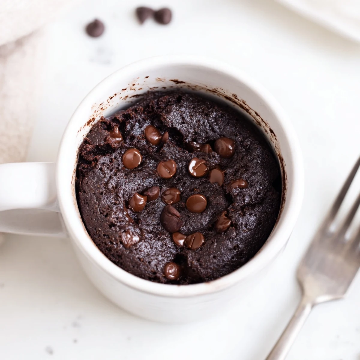 Warm, fluffy chocolate Microwave Mug Cake ready to devour with a dollop of whipped cream on top.