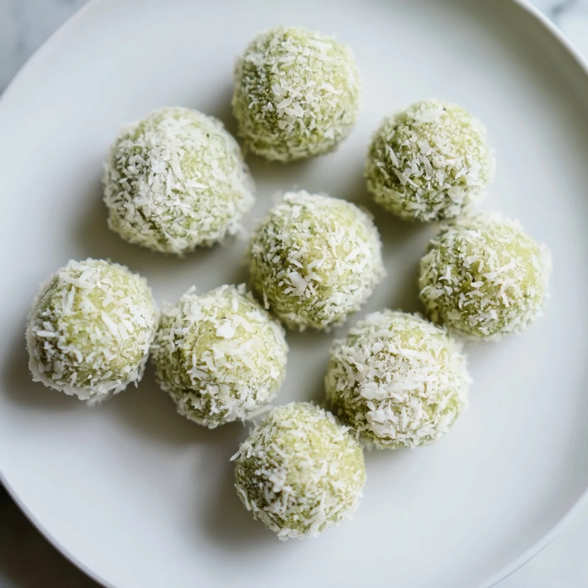 Vibrant green Coconut Matcha Snowball Fat Bombs rolled in fresh coconut, ready to chill.