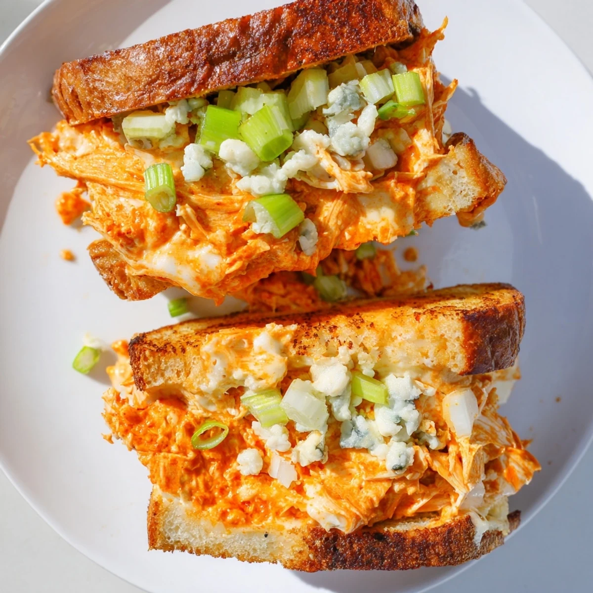 Golden, melted Buffalo Chicken Grilled Cheese, overflowing with cheese and tender chicken visible.