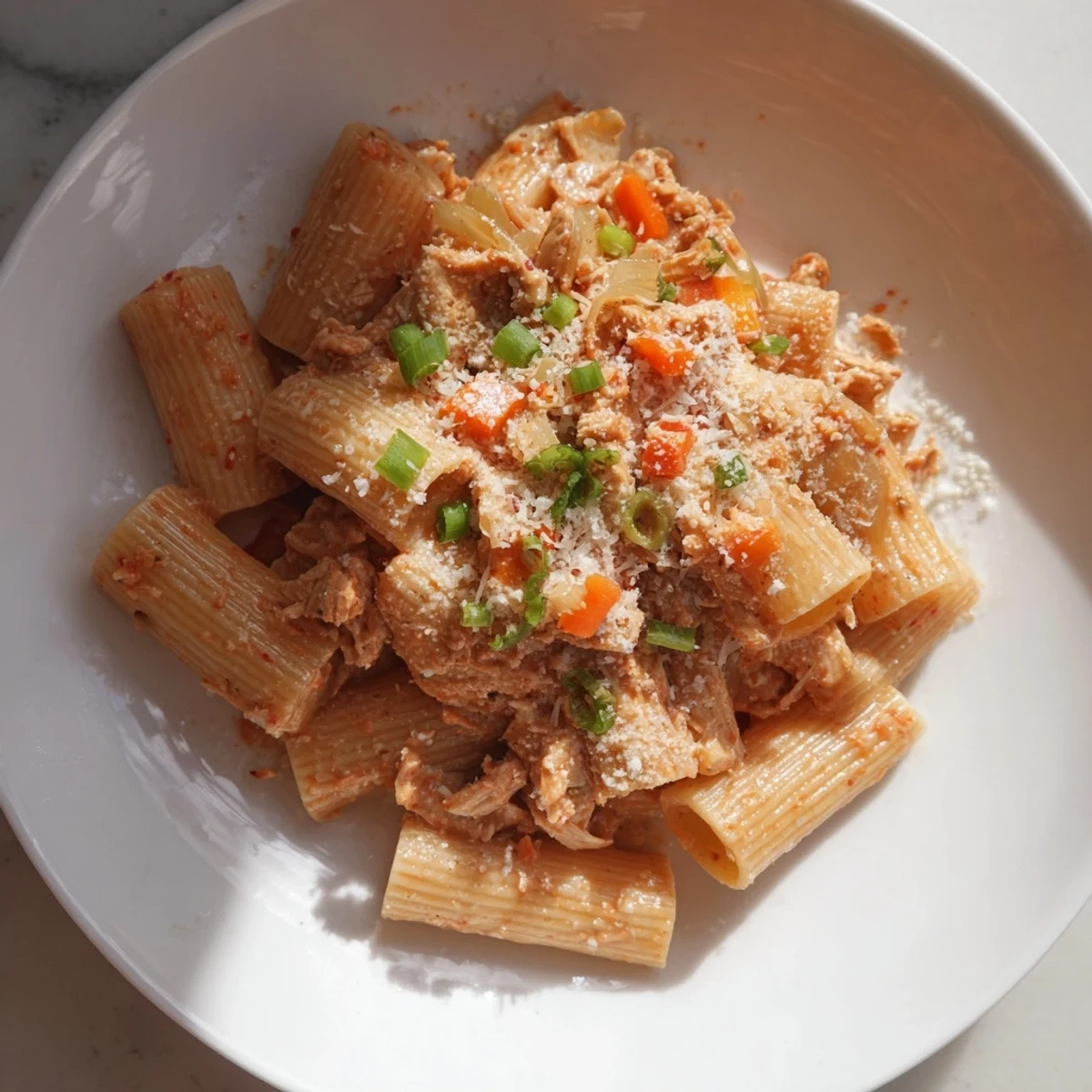 Chaos Cooking Kimchi Ragu Pasta, a steaming bowl of pasta with rich, reddish ragu and green scallion topping.