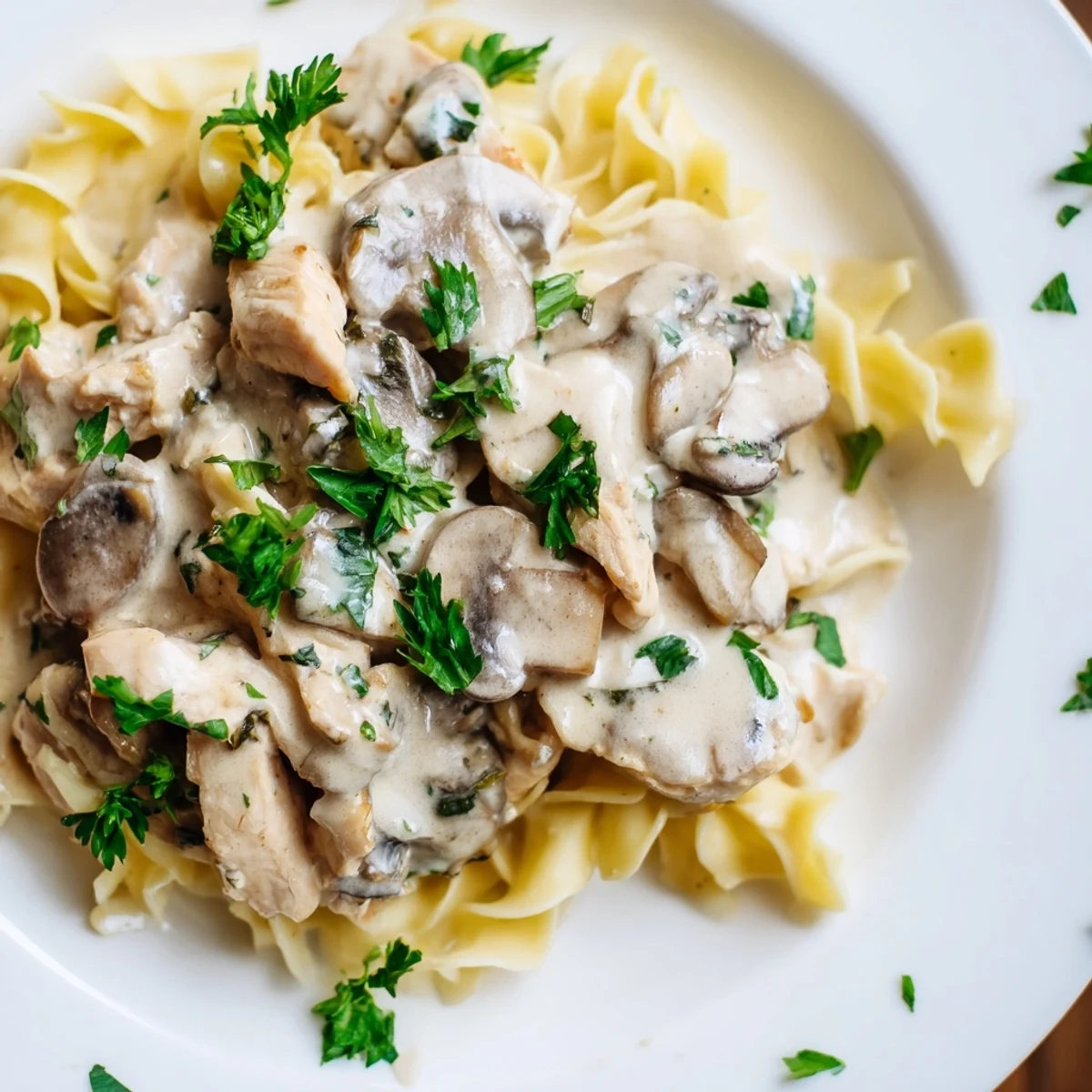 A hearty plate of Chicken and Mushroom Stroganoff featuring juicy chicken, savory mushrooms, and a rich sour cream sauce tossed with egg noodles and garnished with parsley.