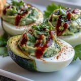 Vibrant deviled eggs made with mashed avocado, lime, and Dijon, finished with a fiery Sriracha kick and fresh cilantro.