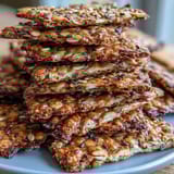 Golden baked seed crackers featuring flax, sunflower, and sesame seeds, ideal for serving with cheese or dips.