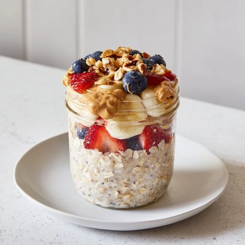 Creamy Overnight Oats jars layered with fresh fruit and swirls of peanut butter.