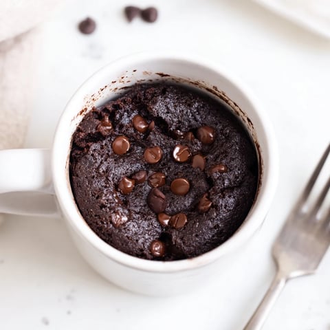 Warm, fluffy chocolate Microwave Mug Cake ready to devour with a dollop of whipped cream on top.