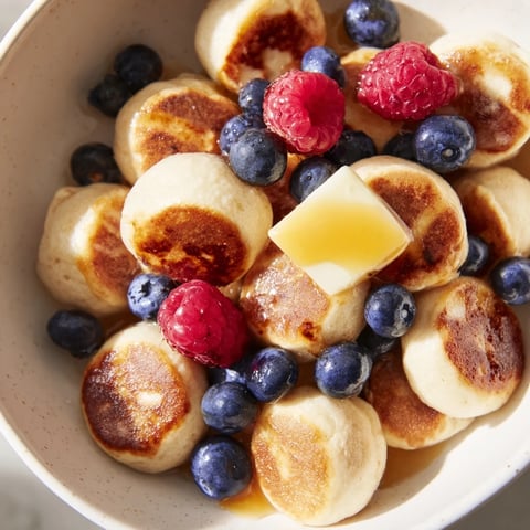 Fluffy pancake cereal topped with sweet syrup and berries, a delightful breakfast treat.