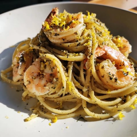 Steaming plate of Lemon Herb Pasta with Shrimp, garnished with fresh herbs and lemon wedges.