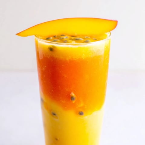 A layered Tropical Sunset Smoothie, vibrant with swirls of mango, passion fruit, and orange.