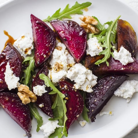 A plated Roasted Beet Goat Cheese Salad with ruby-red beets, creamy crumbled goat cheese, and toasted walnuts over baby arugula.  
