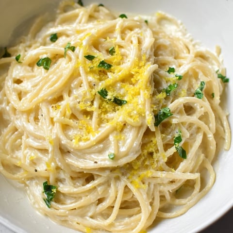 A close-up of Lemon Ricotta Pasta twirled on a fork, showing creamy ricotta sauce clinging to each al dente spaghetti strand.  