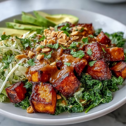 Vibrant Thai Peanut Sweet Potato Buddha Bowl filled with roasted sweet potatoes, crisp broccoli, shredded cabbage, and creamy avocado slices.