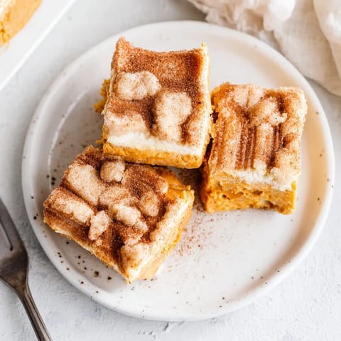 Decadent and creamy pumpkin cheesecake layered over sweet churro crust bars ready to serve.  