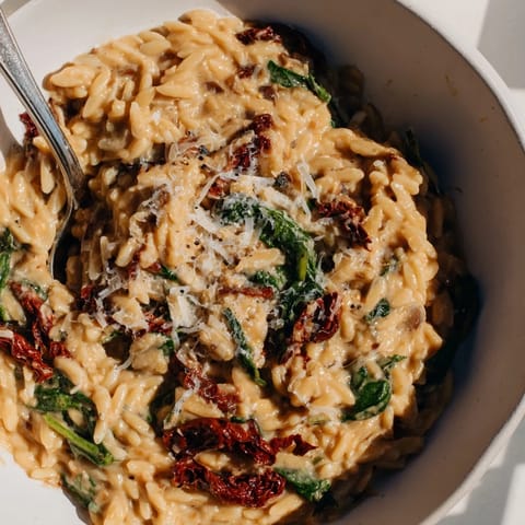 Indulge in this delicious creamy Tuscan orzo bowl garnished with sun-dried tomatoes.  
