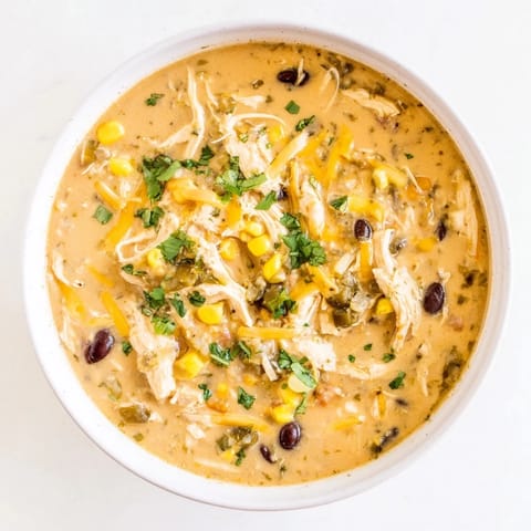 Creamy Chicken Poblano Soup, with melting cheese and visible pieces of chicken, corn, and peppers.