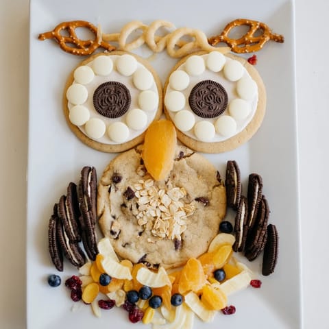 An Owl Hooting Dessert Board presents a whimsical arrangement of sweets with various textures and colors.