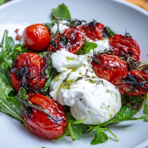 Enjoy a vibrant Charred Tomato Salad with Burrata, drizzled with basil-infused olive oil and balsamic glaze.