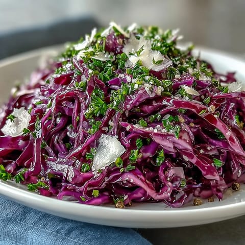 Freshly tossed Red Cabbage Coleslaw with Apple and Parmesan, featuring crisp vegetables and a tangy vinaigrette in a white serving bowl.