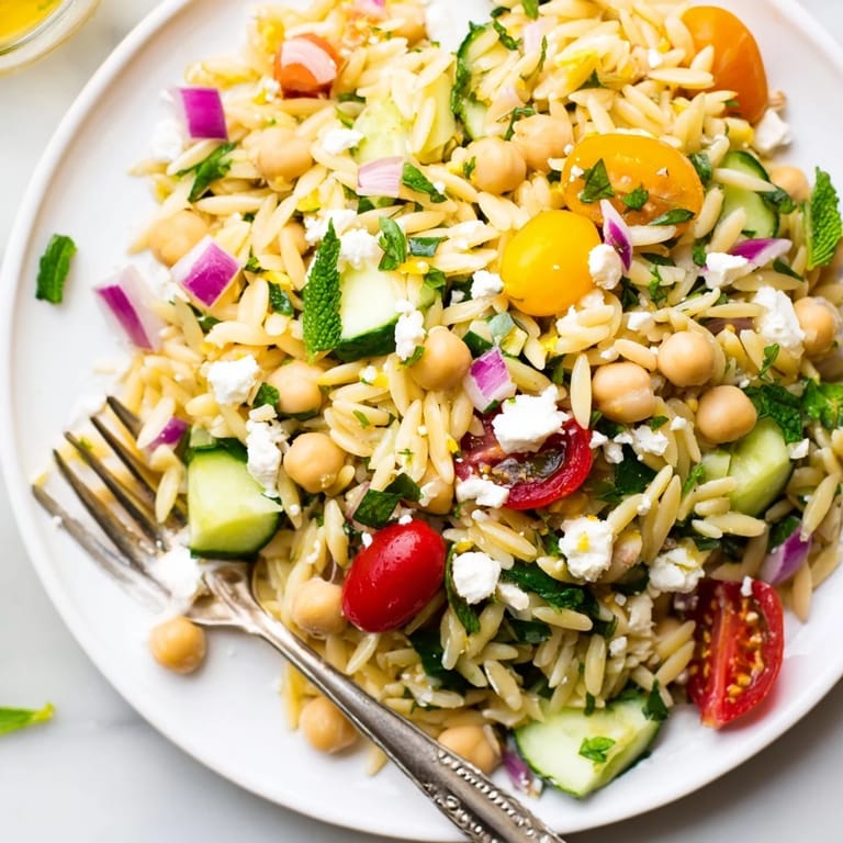 Freshly tossed Lemony Chickpea Orzo Salad with crumbled feta and fresh herbs, drizzled with a zesty lemon vinaigrette and ready to serve.